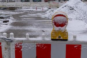 Red and yellow warning reflector covered with snow on construction site barrier photo