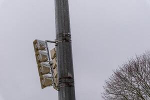 Snow covering outdoor public address loudspeakers system on metal pole in winter season photo