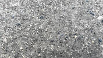 Textured surface of concrete with pebbles and small stones in daylight photo