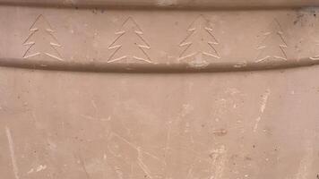 Carved tree patterns on a clay surface show traditional craftsmanship techniques photo