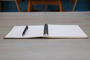 Low angle side view. Lined notebook page with pen on wooden table background. photo