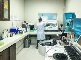 Kupang - August 1, 2024. An analyst in a laboratory is examining a patient's blood sample, surrounded by technological equipment. photo