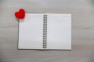 Notebook with lines and hearts on wooden table background. Valentine Day Theme photo