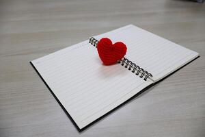 Top view. heart made of yarn on a notebook with lines page for writing. Valentine Day Theme photo