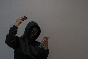 Side view Hacker, masked individuals holding phone and credit cards, call cyber scams, criminal networks stealing information from call centers. photo