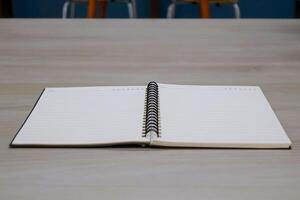 Low angle side view. Lined notebook page on wooden table background. photo