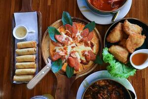 High angle view. The dining table consists of pizza, fried spring rolls, fried fish. photo