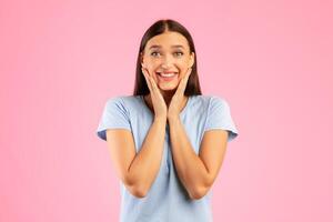 Portrait of excited lady touching cheek with joy isolated over orange studio wall, looking at camera, copyspace photo