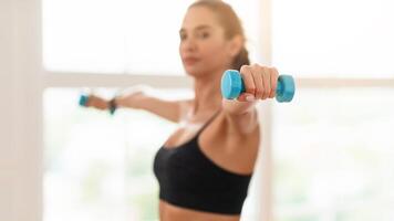 Domestic Training With Weights. Fit woman doing exercises with dumbbells, strengthening her body and arms at home or fitness studio, selective focus on equipment. Female working on her biceps muscles photo