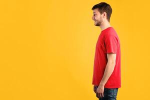 Profile portrait of bearded casual smiling caucasian man posing isolated over blue studio background. Side view of positive guy standing and looking at copy space photo