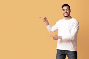Check This. Happy arab couple pointing at copy space in the middle of yellow background, young middle eastern man and woman recommending something, showing free place for your design or advertisement photo