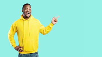Look At This Offer. Excited Black Millennial Man Pointing Fingers Aside Showing Empty Space For Advertisement Text Standing Over Blue Background, Smiling To Camera. Studio Shot. Look There Concept photo