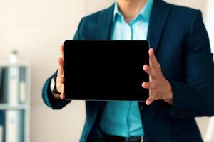 Unrecognizable Arab businessman showing tablet computer with blank screen, offering mockup for website or app at office. Cropped view of millennial employee demonstrating touch pad with copy space photo