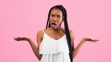 Irritated African American woman showing I DON'T KNOW gesture, shrugging shoulders on pink studio background. Annoyed black lady cannot understand something, gesturing WTF photo
