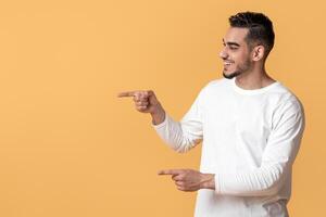 Great Promo. Happy Arab Couple Pointing At Copy Space In The Middle With Two Hands, Cheerful Young Spouses Demonstrating Empty Place On Yellow Background For Your Advertisement, Panorama photo