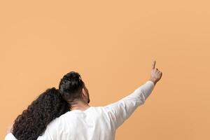 Man And Woman Hugging Over Yellow Background And Pointing At Copy Space While Relaxing On Floor In Studio, Unrecognizable Young Couple Demonstrating Free Place For Ad Or Design, Panorama photo