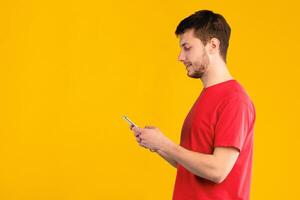 Modern Lifestyle, Technology And Communication Concept. Side view portrait of smiling bearded man chatting on cellphone, isolated over blue studio background, free space. Young guy using smartphone photo