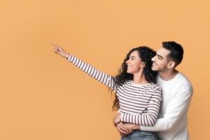 Family Offer. Happy Millennial Arab Spouses Embracing And Pointing Aside At Copy Space, Smiling Middle Eastern Couple Demonstrating Free Place For Advertisement Over Yellow Background, Panorama photo