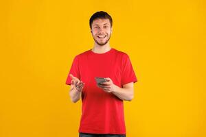 Amazing Application. Portrait of excited emotional man using smartphone standing and posing isolated on blue studio background, free space. Smiling guy looking at camera, holding gadget photo