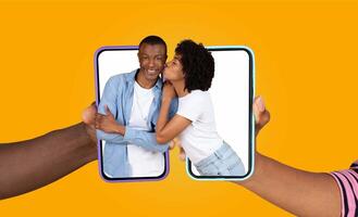 A loving African American couple smiles and embraces while interacting with their smartphones. They showcase their connection through a digital application that enhances their relationship. photo
