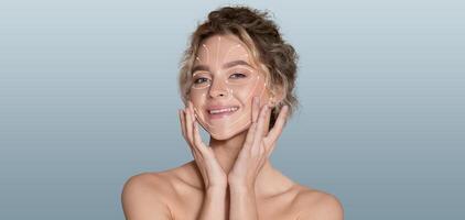 A woman enjoys her pampering skin care routine, gently applying products to her face with a calm expression. The isolated background emphasizes relaxation and beauty tranquility. photo