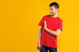 Keep Distance, Don't Stay Close To Me. Displeased young guy with disgusted facial expression raising hand, showing stop gesture with palm to the side, standing isolated over blue studio background photo