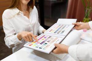 Ladies are enjoying a pampering session at a salon, choosing from a variety of vibrant nail polish colors for their manicure. The atmosphere is stylish and relaxing. photo