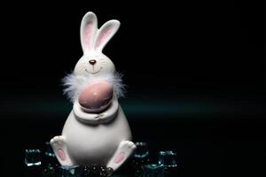 Sculpture of a white rabbit with Easter eggs on black background with ice cubes photo