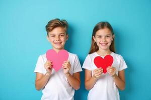 two children holding heart shaped paper on blue background photo