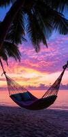 A hammock is hanging over the ocean with a beautiful sunset in the background photo
