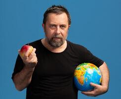 Man holding an apple and a globe, symbolizing knowledge and global awareness through food choices photo