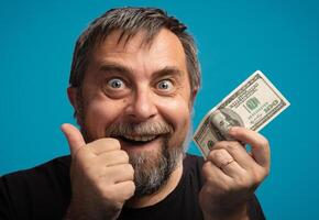 Happy man holding a dollar bill with excitement in front of a blue background photo