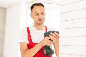 building, renovation, technology, electricity and people concept - builder with screwdriver fixing socket indoors photo