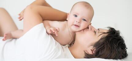 happy family. Mother and baby playing and smiling on bed photo