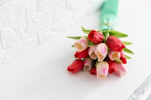 Bouquet of spring tulips with different color flowers wrapped in paper for present on white background photo