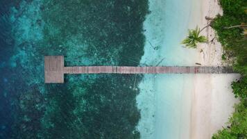 Woman running on pier and jump to ocean on tropical beach. Drone view, top down video