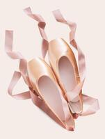 Pastel pink ballet shoes background. New pointe shoes with satin ribbon lay on white isolated backdrop photo