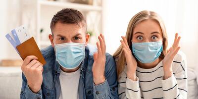 Global quarantine concept. Portrait of shocked couple in protective masks with canceled flight tickets photo