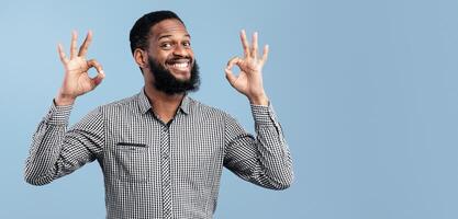 I'm Fine. Close up portrait of happy african business man doing ok gesture isolated over blue studio wall, copyspace photo