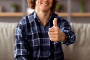 I Like It. Unrecognizable Guy Gesturing Thumbs Up To Camera Approving Something Posing Sitting On Couch At Home. Contented Customer Showing Thumbs-Up Gesture Advertising Service. Cropped photo