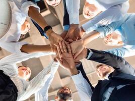 Business Unity And Teambuilding. United Colleagues Standing In Circle Holding Hands Together In Modern Office. Bottom View photo