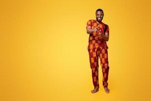 Handsome cheerful black guy in authentic clothes flirting over yellow studio background photo