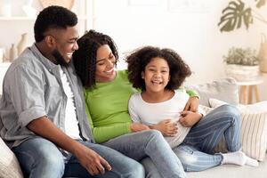 Happy african family, mother father and daughter laughing together and having fun at home, copy space photo