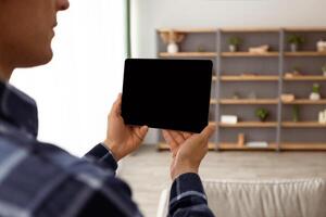 Guy Holding Digital Tablet Computer With Blank Screen Over Living Room Background Standing Indoors. Designer Using Interior Design Application. Gadget, Technology Concept. Mockup photo