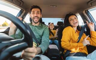 We are going on vacation. Happy family of three driving in their automobile, dancing to music and singing favorite song, enjoying travelling by car photo