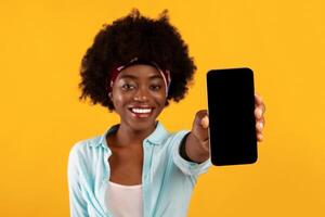 Cheerful Black Bushy Lady Showing Phone Empty Screen Advertising New Mobile Application For Smartphone Over Pink Background In Studio. Great App For Your Cellphone Concept. Check This Out. Mockup photo