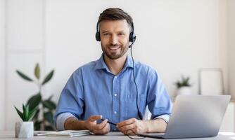 Portrait of smiling male customer service operator in headset posing at workplace, looking at camera, portrait of handsome hotline manager sitting at desk with laptop in white office, copy space photo