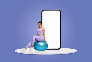 A woman dressed in purple activewear balances on a stability ball, engaging in fitness activities while a large smartphone stands behind her against a blue backdrop. photo