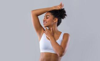 Happy black girl smelling her fresh armpit over grey background, putting hand up, copy space photo