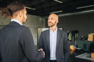 Two business professionals engage in a firm handshake inside a sleek, contemporary office, symbolizing successful collaboration and agreement during daylight hours. photo